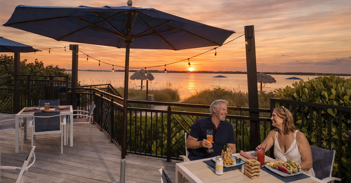 Couple dining outdoors by the water at sunset.
