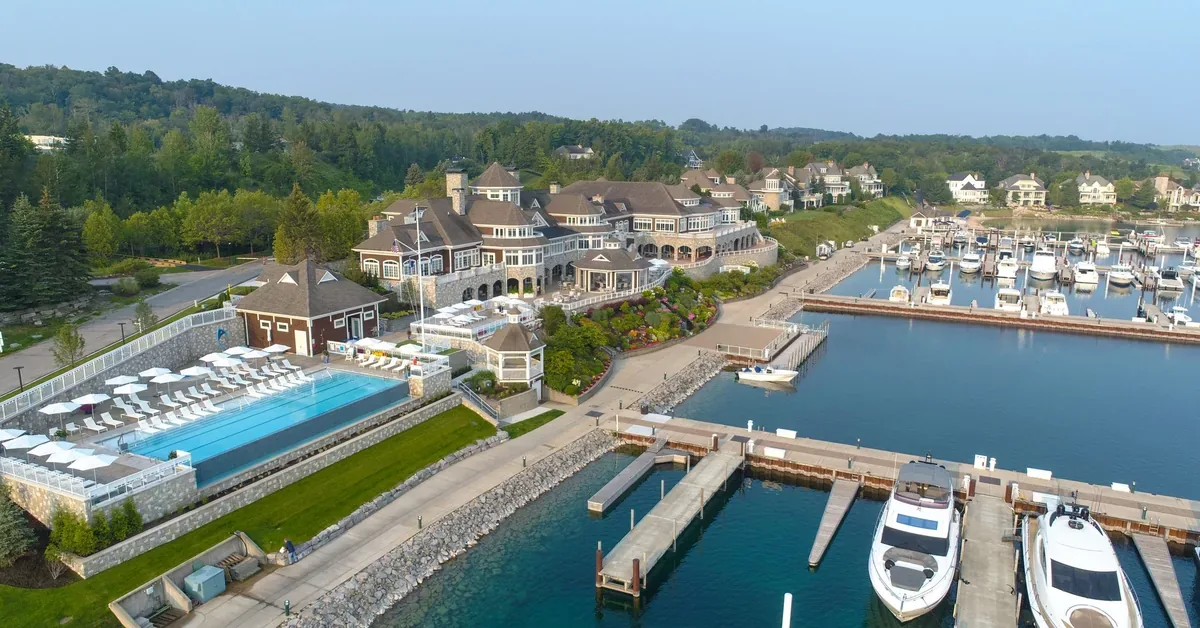 Luxury waterfront estate features marina with yacht slips, infinity pool, and sprawling clubhouse overlooking pristine harbor waters.