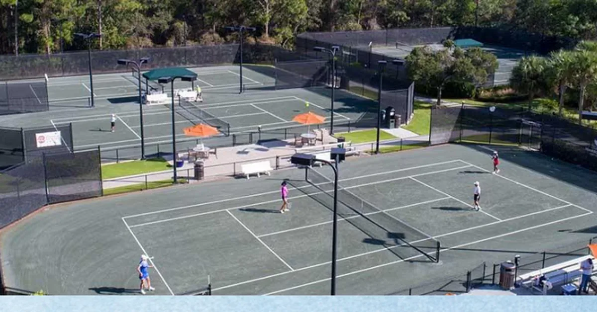 Aerial view of modern residential tennis courts and basketball facilities surrounded by lush landscaping and recreational amenities.