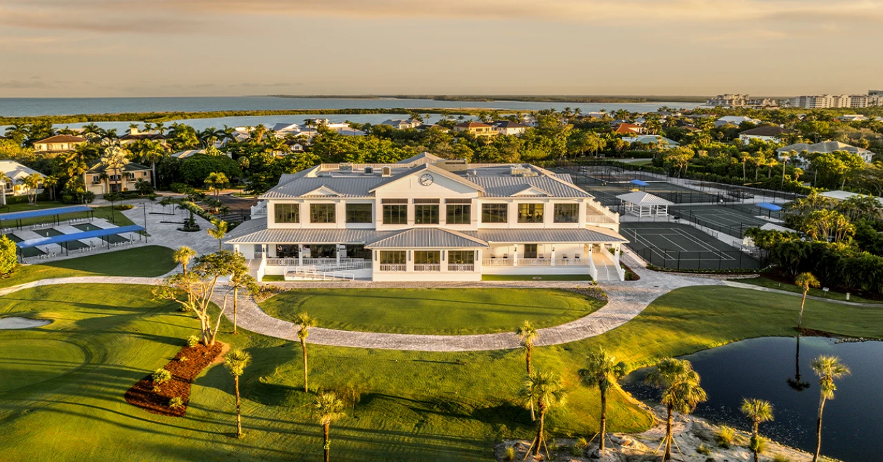 Aerial view of a large white clubhouse with golf greens
